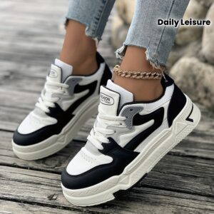une paire de chaussures sportives décontractées pour femmes, confortables et respirantes en maille classique noir et blanc à bout rond avec lacets série "sneakers classiques" plates adaptées pour les loisirs quotidiens et sorties printanières